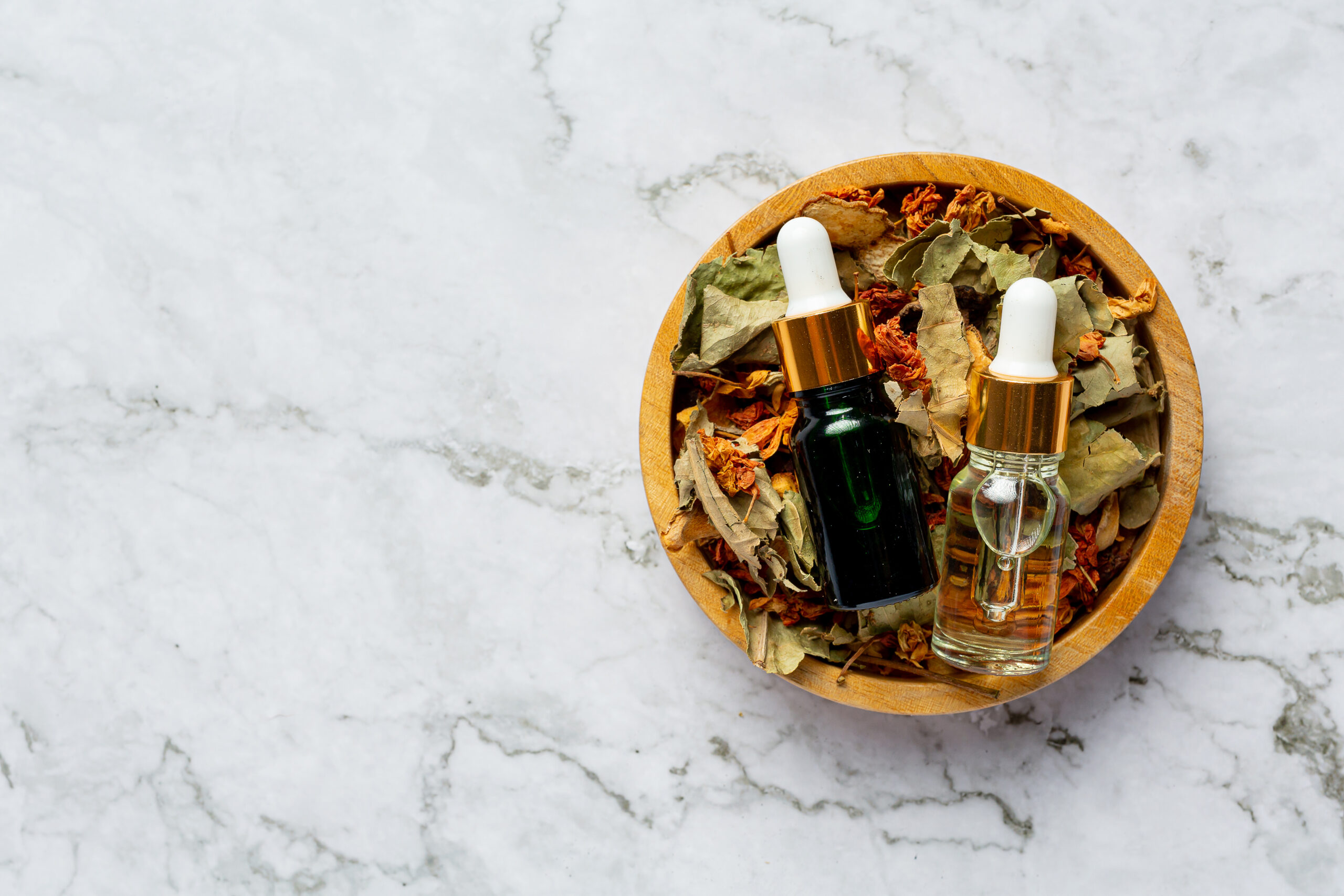 bottles of herbal spa treatment oil put in wooden bowl